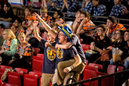 Jason Hicks raises a hand in the air as Luke Krolczyk leaps on his back. Helping his teammates cheer on their team Ranger Robotics is Zac Case.